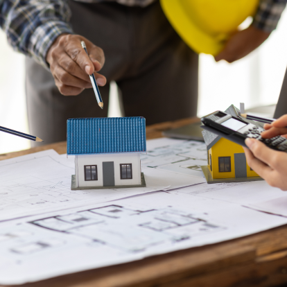 Planning a house addition project, people with blueprint and helmets in a meeting.